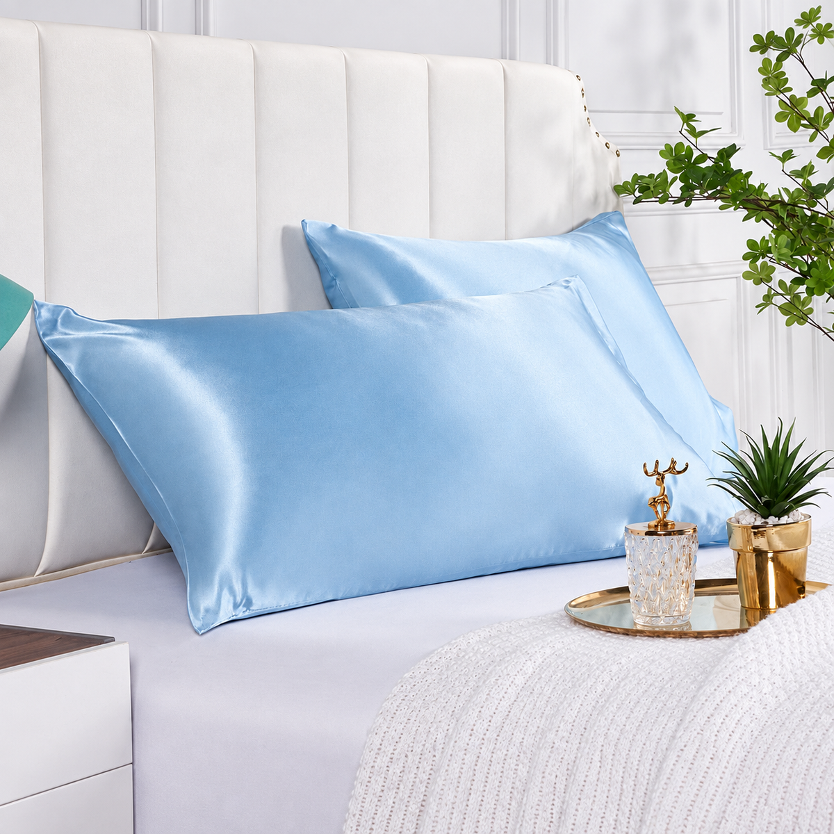 Light blue satin pillowcases styled on a bright modern bed